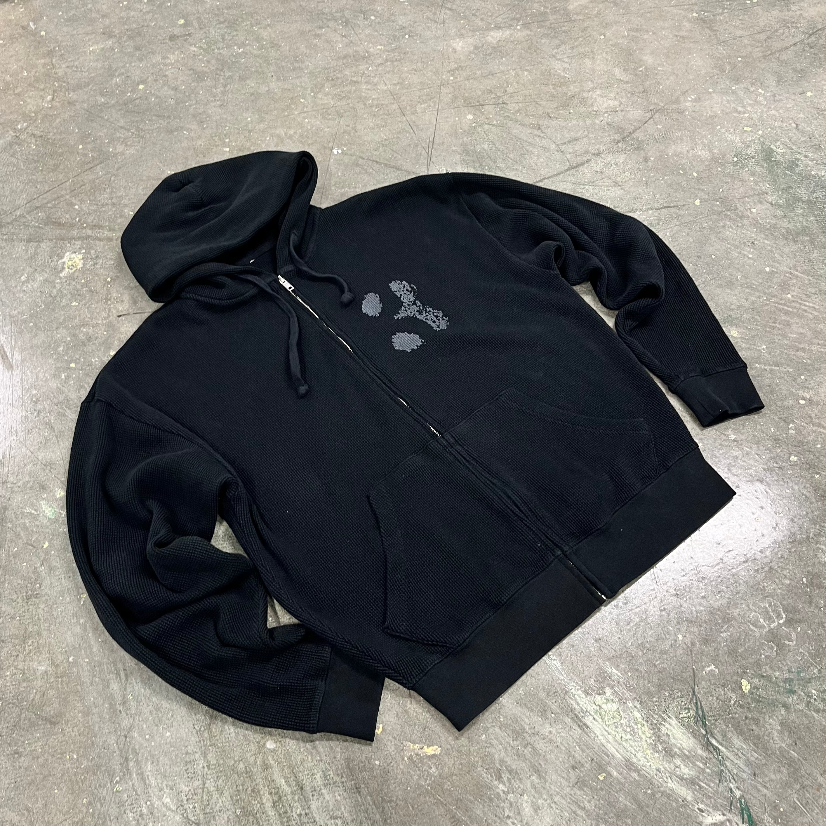 Black hoodie with floral design on a gray surface