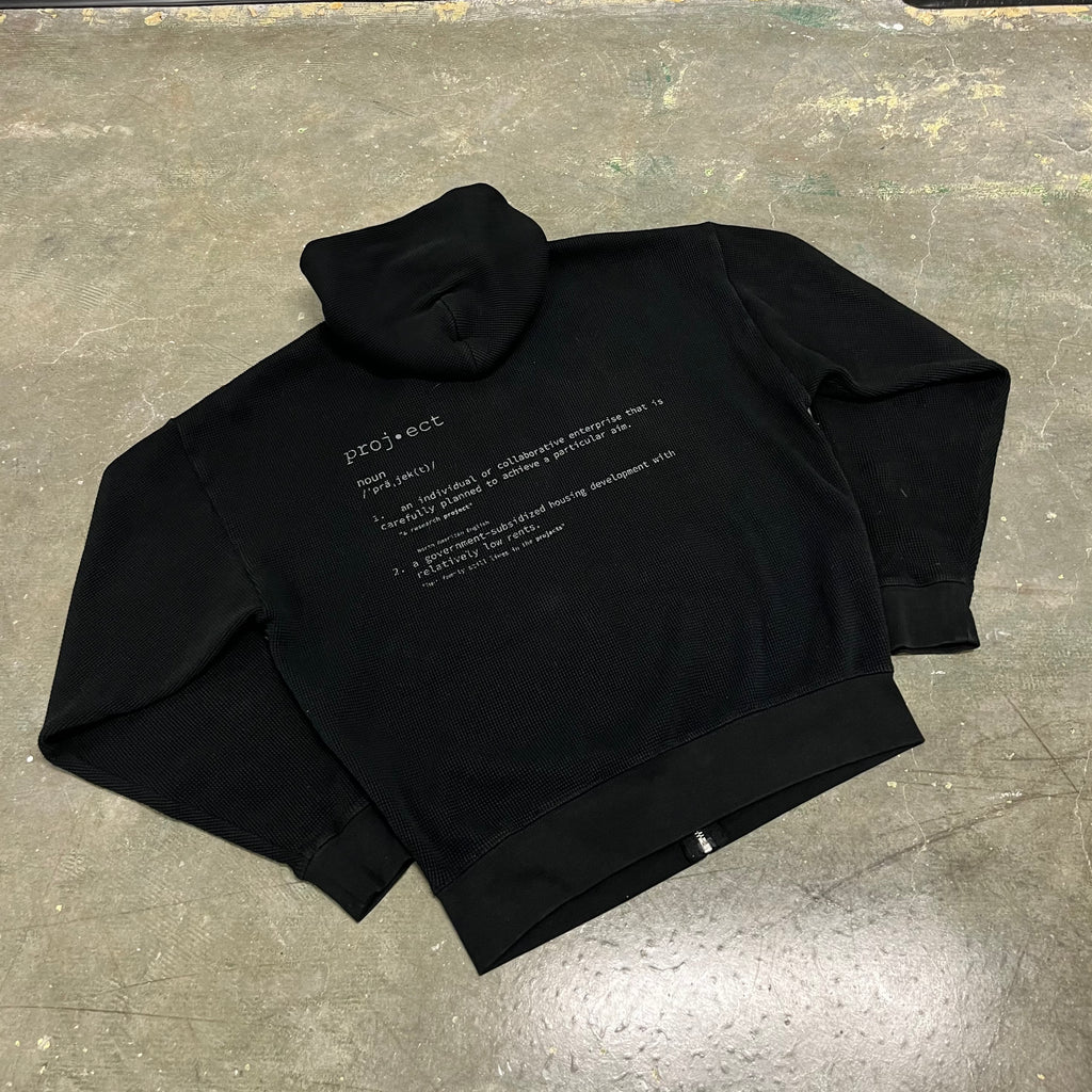 Black hoodie with text on a gray concrete surface