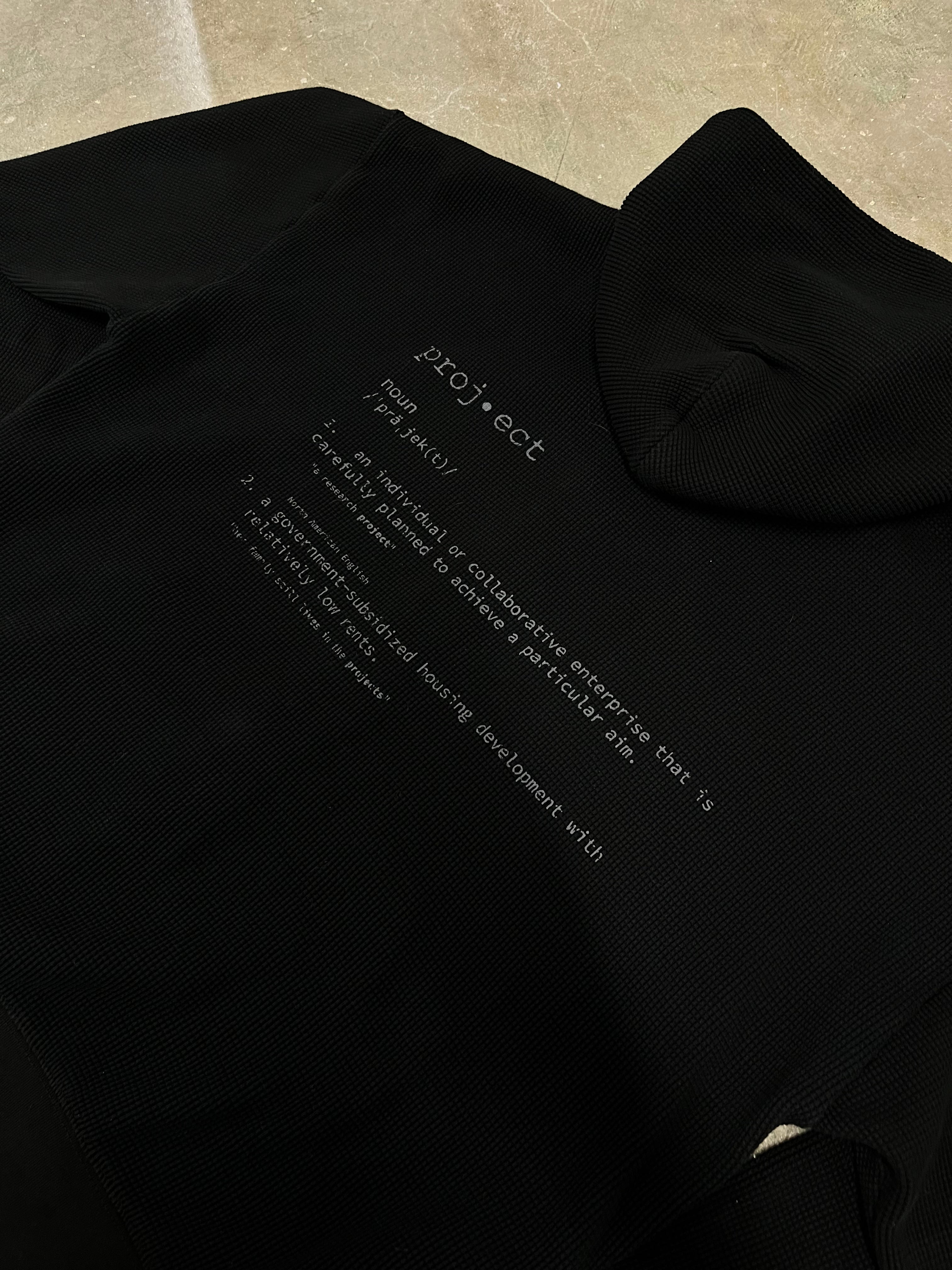 Black shirt with white text on a beige surface